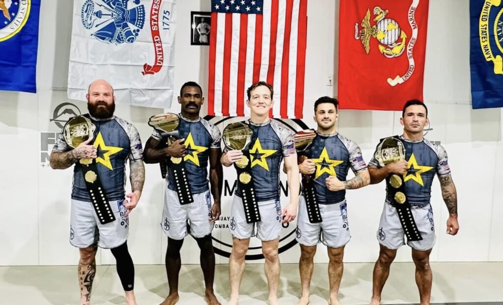 Enlisted Nine Fight Company wrestling students holding belts from winnings.