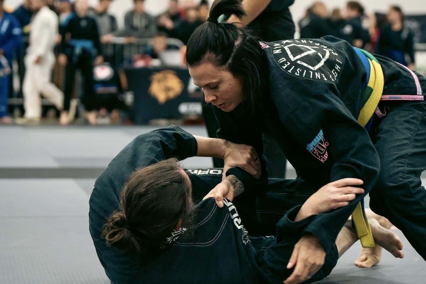 Enlisted Nine Women grappling during BJJ self-defense lesson wearing gi uniforms.
